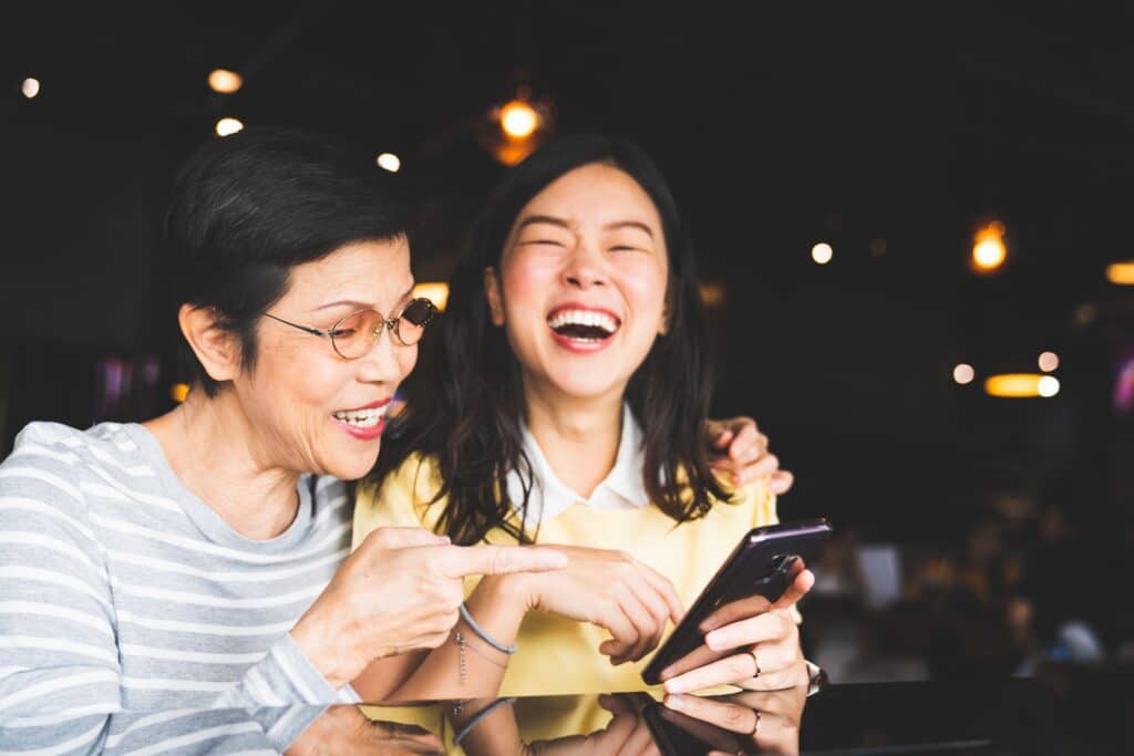 mother and daughter laughing as they look at her smartphone