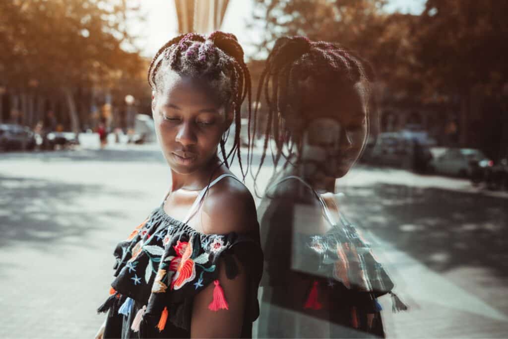 young black woman standing up against a reflective window