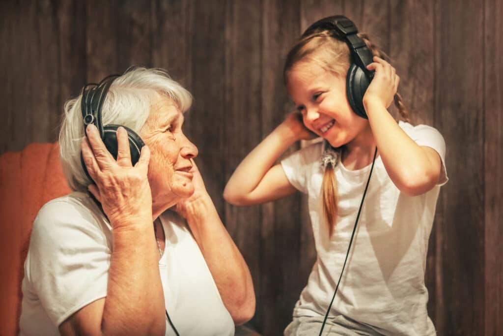 grandma and granddaughter listening to headphones together