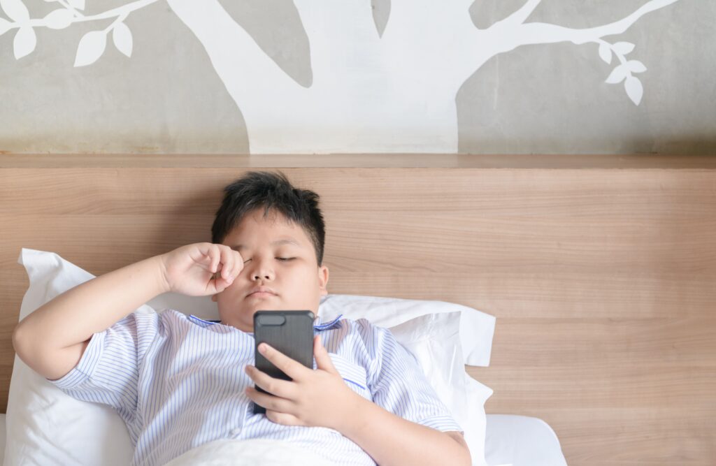 tired little boy looking at phone