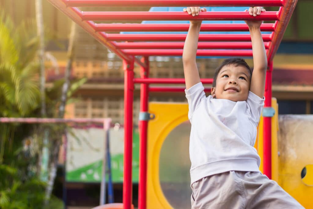 little boy climbing on monkey bars