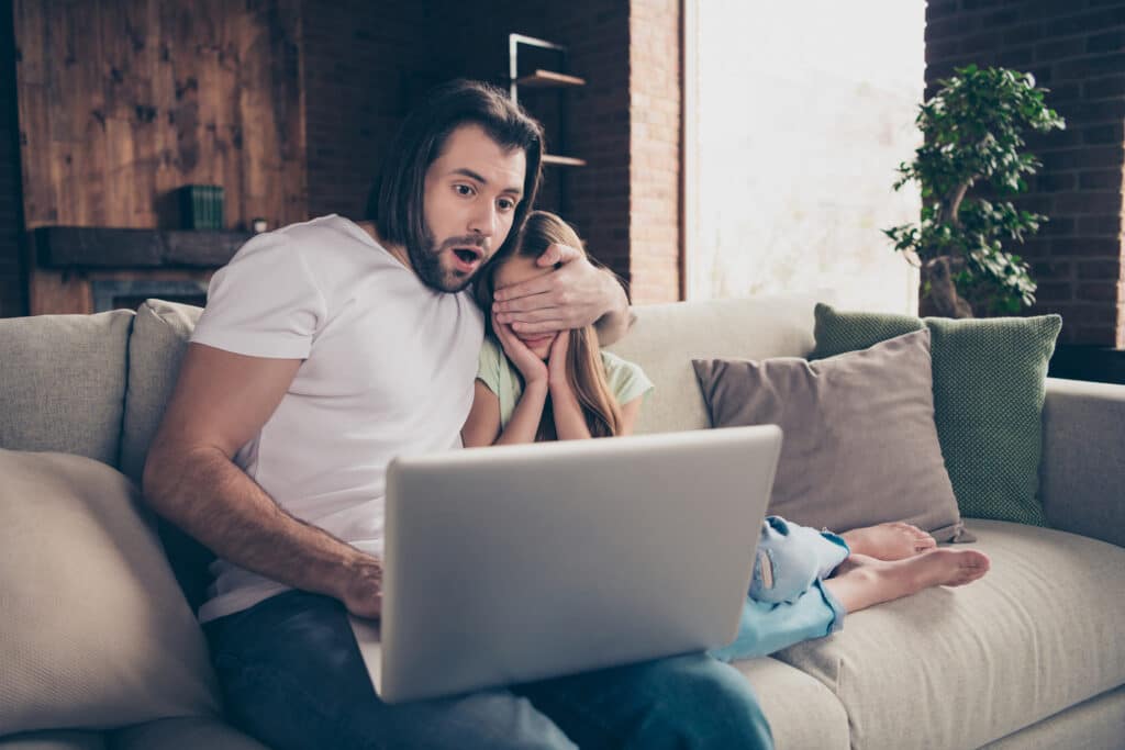 father shielding daughters eyes from laptop