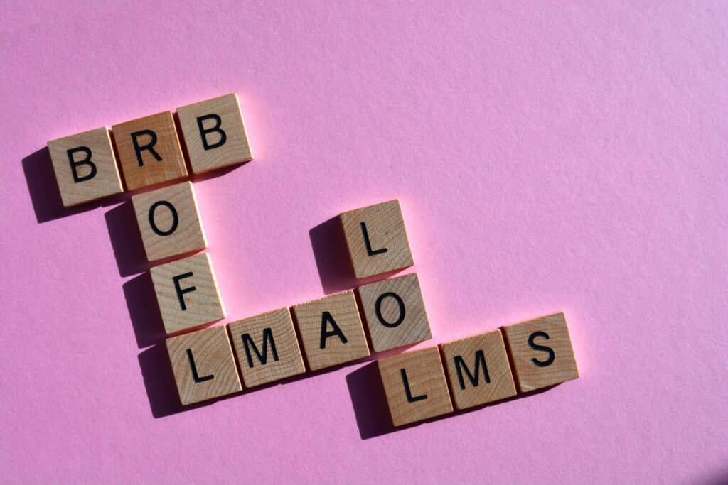 scrabble pieces showing slang words on pink acronyms