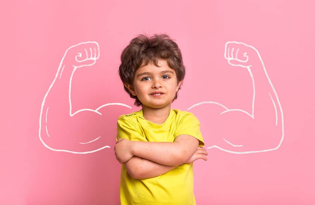 little boy with strong muscular arms drawn on the wall behind him