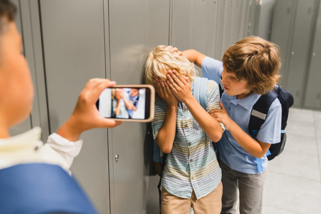 boy bullying another boy while another records on his phone
