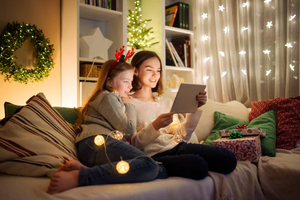 young girl and sister or mom look at an ipad together during the holidays