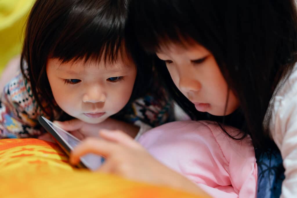 two little girls looking closely at a phone screen