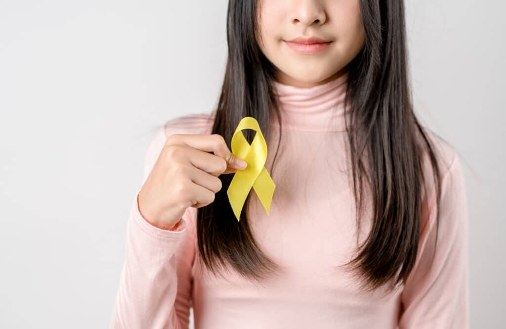 young girl holding yellow awareness ribbon