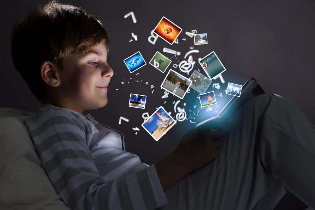 young boy looking at ipad with images coming off the screen