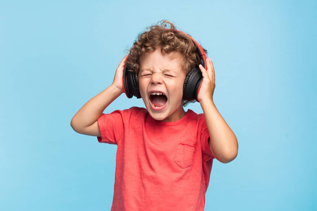 small boy listening to headphones and screaming