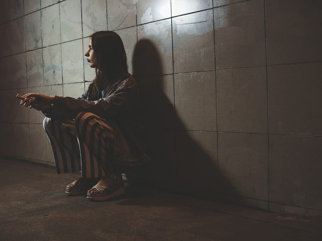 teen girl sitting on the floor in a dark hallway