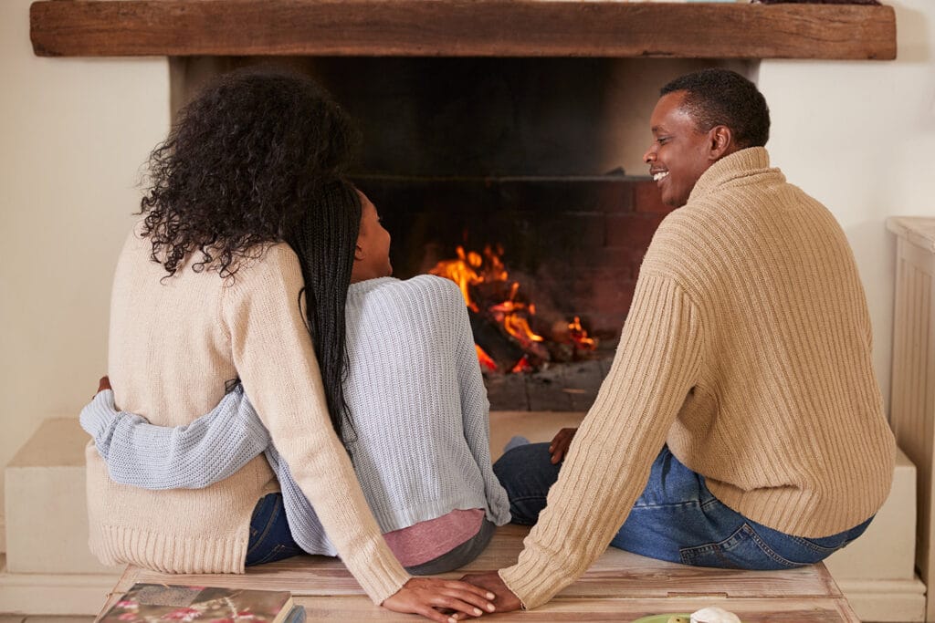 family of color smiling in front of a fireplace