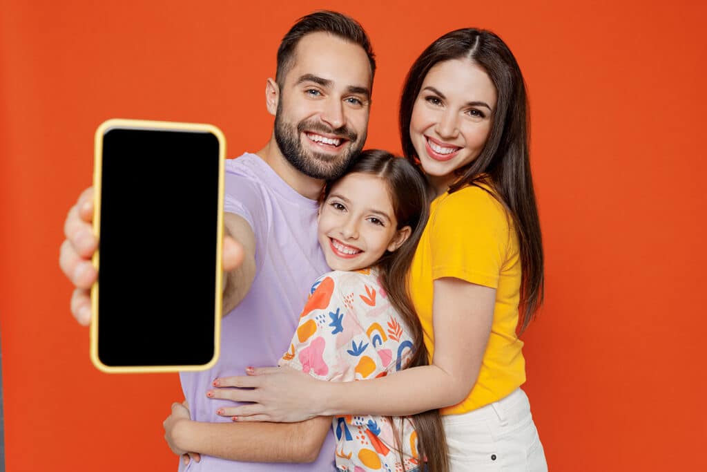 happy family hugging holding up a cellphone