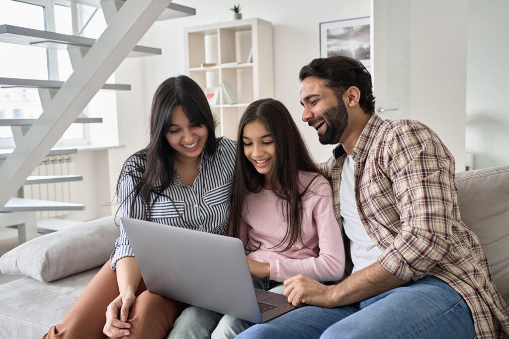 family smiling looking at a laptop