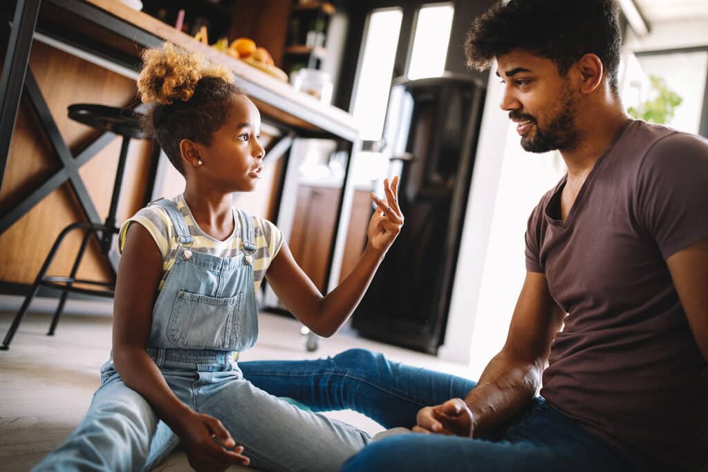 father and young daughter talking in a kitchen