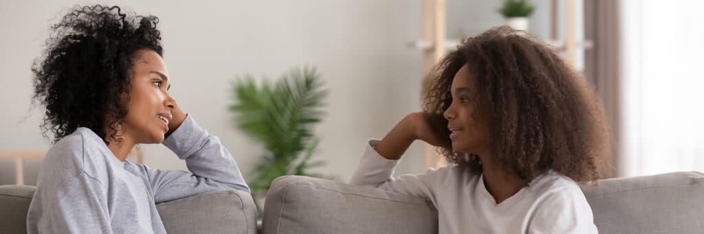 mother and daughter sitting on a couch talking