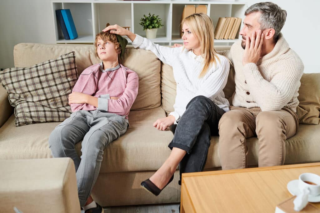 parents looking concerned for son on a couch